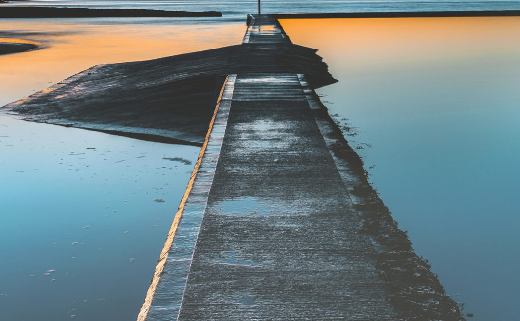 photograph of a path into the sea at sunrise or sunset